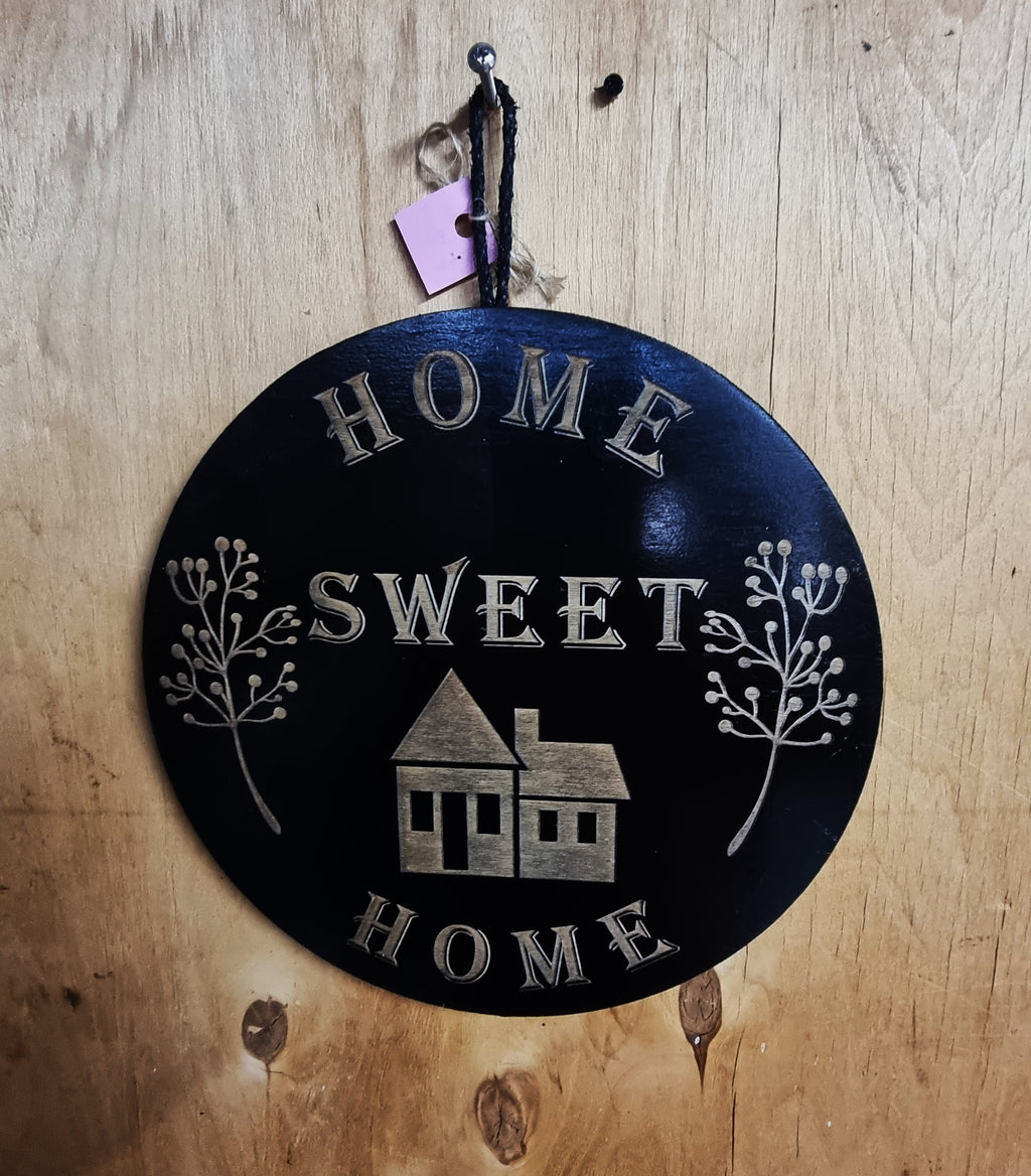 Round black plywood wall sign with laser-engraved Home Sweet Home design and botanical sprigs, 280mm diameter